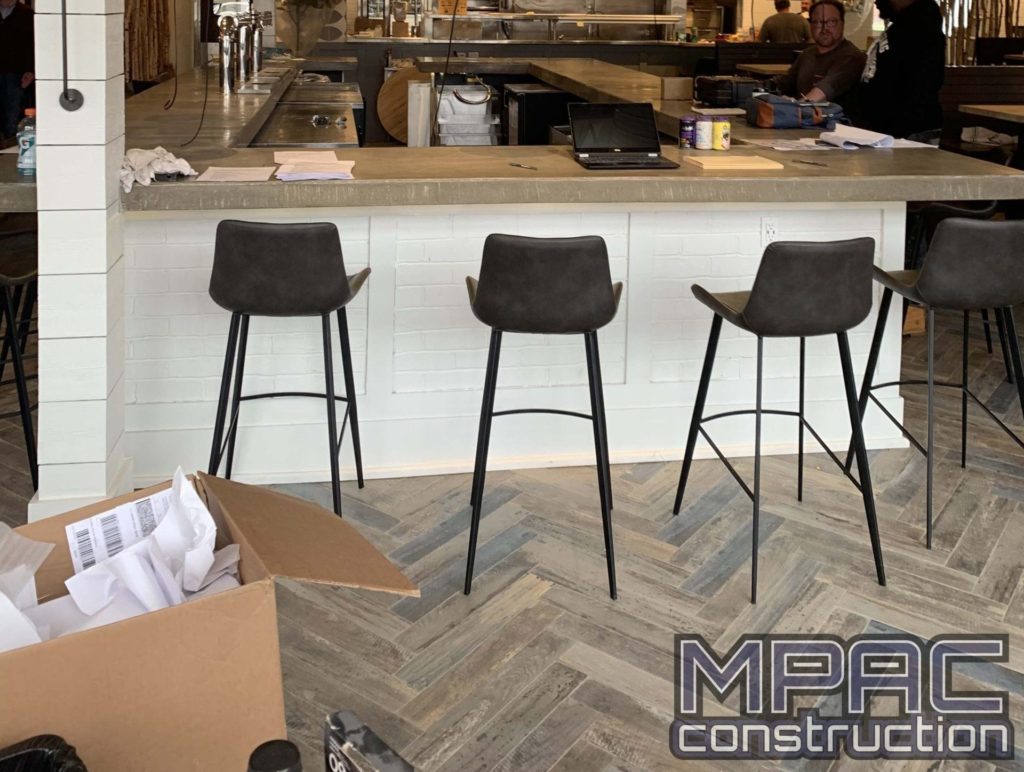 Commercial construction work in progress at a vibrant bar scene, with workers renovating and remodeling the space to create a modern and inviting atmosphere. We also offer home improvement!